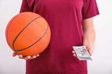 Woman holding money and basketball ball on white background