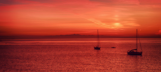 Beautiful colorful sunset at the sea with two sailing boats . Beauty world natural outdoors travel background