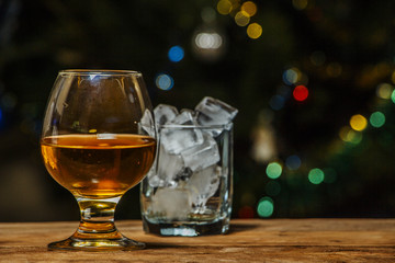 A glass of cognac or whiskey on a village table in the background of lights.