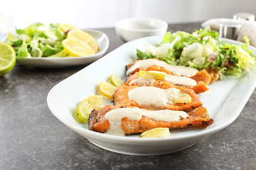 Tasty rainbow trout fillets with sauce on plate, closeup