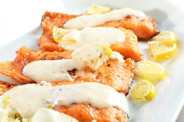 Tasty rainbow trout fillets with sauce on plate, closeup