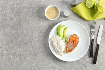 Tasty rainbow trout steak with garnish and sauce on table, top view