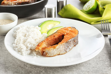 Plate with tasty rainbow trout steak and garnish on table