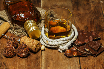 A glass of cognac or whiskey on a rustic table with chocolate and truffles. © yuriivd