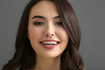 Young beautiful smiling woman on grey background, closeup