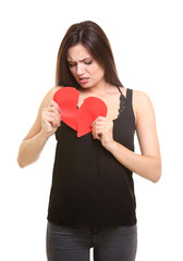 Young woman holding torn paper heart on white background