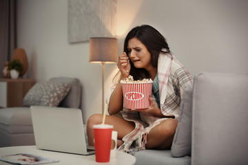 Young woman crying while watching movie at home