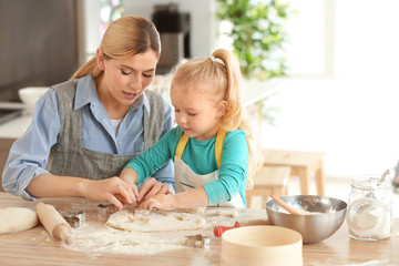 Mother and daughter with dough at table indoors