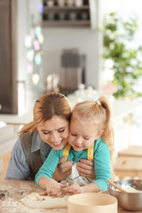 Mother and daughter with dough at table indoors