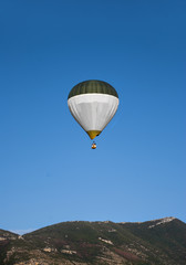 Fototapeta premium A hot air balloon, in flight to the mountains