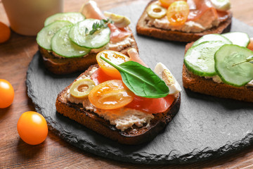 Slate plate with tasty fresh bruschettas on table