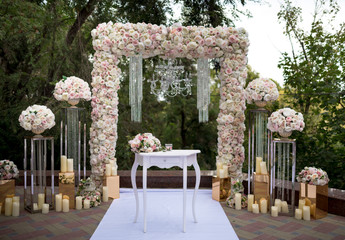 Elegant pink and beige wedding arch with fresh flowers of pions
