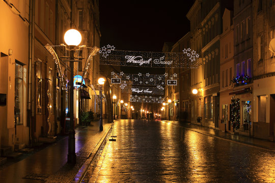 Ulica w centrum miasta Brzeg w nocy po deszczu w złotym kolorze.