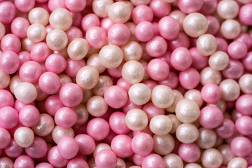 Closeup of a pile of pink and white sugar pearls (cake decor), from above