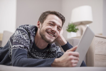 Young man with tablet computer in their hands, on the couch at home.