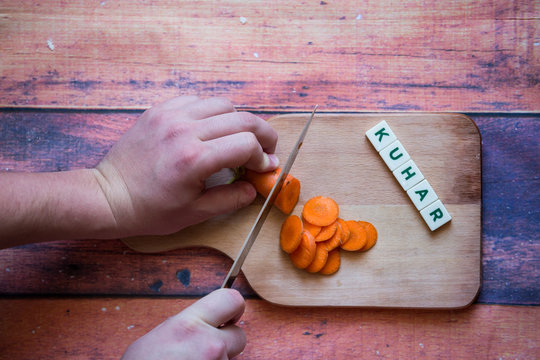 Chef Is Cutting Carrot On A Wooden Cutting Board With Sharp Knife And Word For Bosnian, Serbian, Croatian Chef Written With Box Letters.