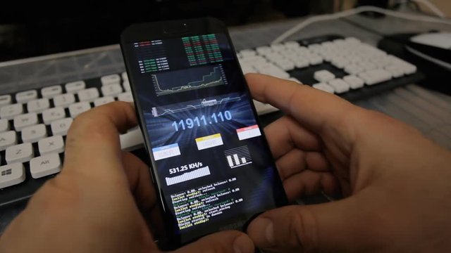 Browsing or watching on a smartphone: a fake portal showing live real-time statistics about virtual digital crypto-currencies like bitcoin. Background: streaming blue data.
