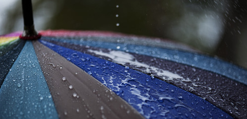 Panorama of Close-up  umbrella in rainbow colors in rainy autumn day, blur focus