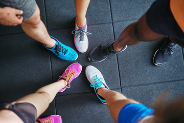 Diverse people wearing running shoes standing in a gym - obrazy, fototapety, plakaty
