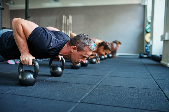 Fit people doing pushups on weights in a gym class