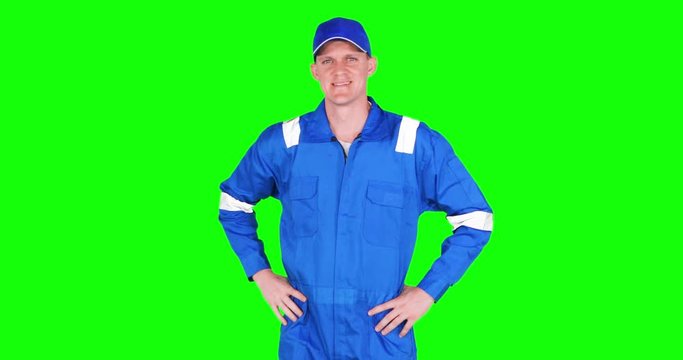 Male Caucasian auto mechanic fixing his hat with hands on waist, shot in 4k resolution with green screen background