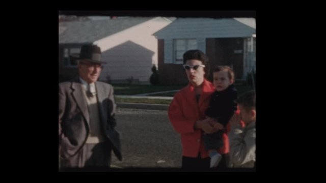 1960 Family with baby chatting on suburban street