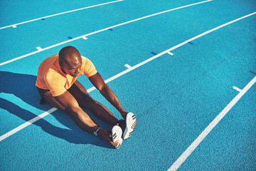 Young athlete stretching on a running track before training