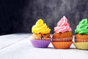 Tasty cupcakes on wooden background. Birthday cupcake in rainbow colors