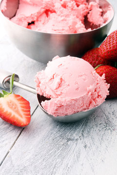 Delicious strawberry ice cream scoop with fresh strawberries on wooden background