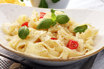 fettucine pasta white cream sauce with tomato and basil in white plate - Italian food style
