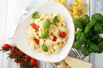 fettucine pasta white cream sauce with tomato and basil in white plate - Italian food style
