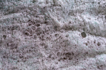 gray texture of old wiped to holes fabric of artificial and natural fibers, abstract background