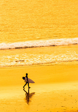 Surfer Walking On California Beach At Sunset