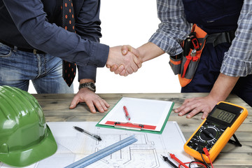 Architect and young electrician technician shake hands in front of a residential building project
