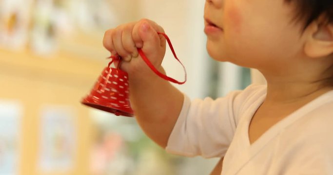 cute baby playing small red bell in christmas day