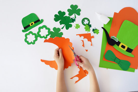 Top view.  Children's hands cut out a mask from paper for a St. Patrick's Day