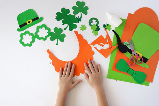 Top view.  Children's hands cut out a mask from paper for a St. Patrick's Day