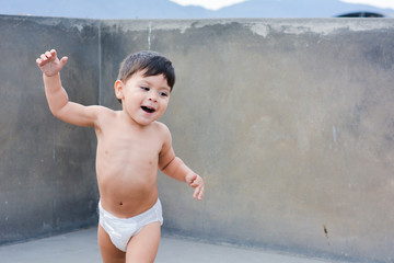 Active little latin boy in diaper dancing.