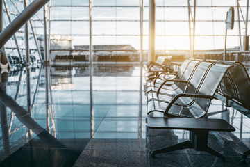 Rij moderne stoelen gemaakt van zwart metaal met kleine plastic tafels aan de zijkanten in een eigentijds licht interieur van een luchthaven- of treinstationdepot, met kopieerruimte voor reclame of sms