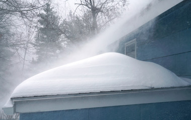 Obraz premium Winter wind blowing thick snow on the roof in blizzard