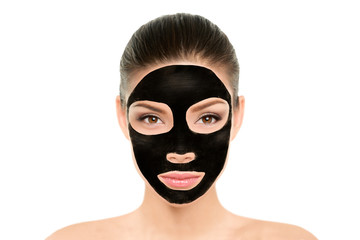 Black charcoal mask facial treatment Asian beauty woman. Wellness and spa purifying peel off mask face portrait, isolated on white background. Cleansing skin care to remove blackheads and clean pores.