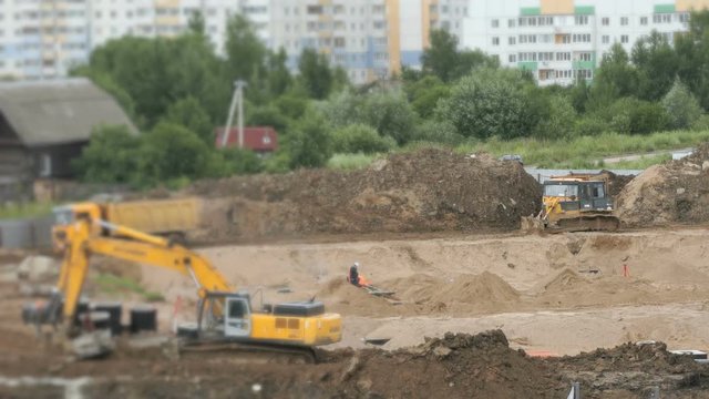 Construction vehicles and builders on construction site in a summer season