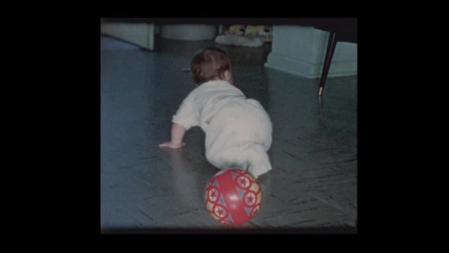 1960 Happy infant baby boy crawling around slippery floor