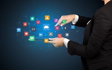Hand holding tablet and application icons above