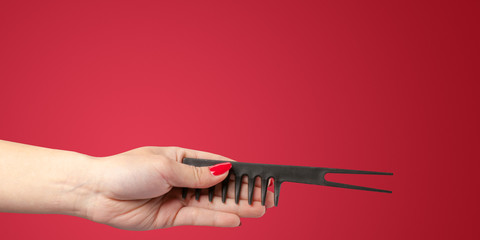 Woman hand with a hair dresser's tools and accessories isolated on color background