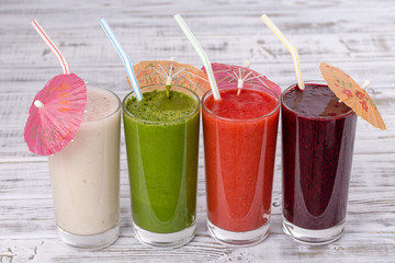 Fresh avocado, strawberry, blueberry and banana smoothie on white wooden table, assorted protein cocktails with fresh fruits. Four drinks