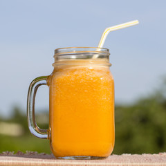 Glass mug of yellow smoothies from carrot juice, lemon, honey and banana