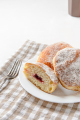 zweieinhalb 'Berliner' Pfannkuchen mit Gabel und Tasse auf weißem Teller und Handtuch
