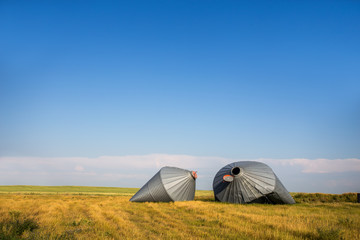 Two crumpled metal grain storage bins damaged by wind in a afternoon rural summer landscape