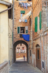 Fototapeta na wymiar Walking trough an archway in a quiet alley - Siena, Italy